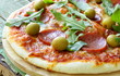Photo: Pepperoni pizza with tomato sauce and herbs on a wooden board Pepperoni pizza with tomato sauce and herbs on a wooden board