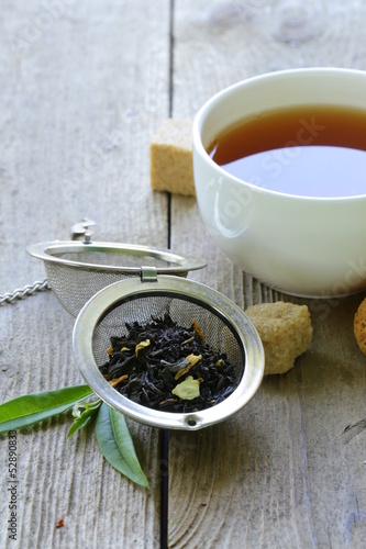 Photo: black tea leaves in a metal strainer on a wooden table black tea leaves in a metal strainer on a wooden table