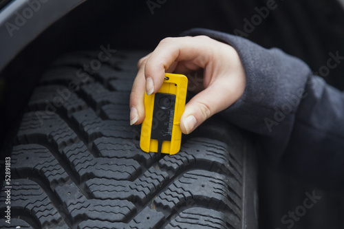 Photo: Frau misst Reifenprofil eines Autoreifen Frau misst Reifenprofil eines Autoreifen