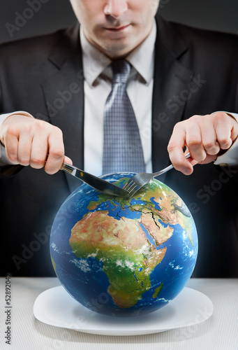 Photo: Greedy businessman cutting planet Earth Greedy businessman cutting planet Earth