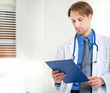 Young doctor reading a clipboard