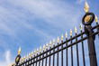 Iron fence with golden peaks on the blue sky background
