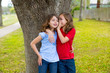 kid friend girls whispering ear playing in a park tree