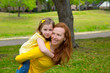 Daughter and mother piggyback smiling in park outdoor