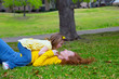 Daughter and mother playing lying on park lawn
