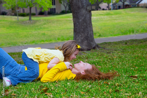 Photo: Daughter and mother playing lying on park lawn Daughter and mother playing lying on park lawn