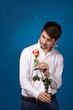 Young man looking to red rose
