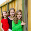 Grils group in a row smiling in a wooden fence
