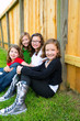 Grils group in a row smiling in a wooden fence