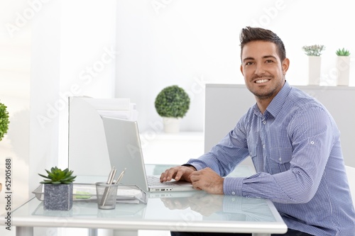 Photo: Happy businessman working on laptop Happy businessman working on laptop