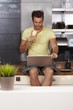 Young man using laptop on kitchen counter
