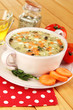 Nourishing soup in pink pan on wooden table close-up