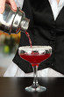 Barmen hand with shaker  pouring cocktail into glass,