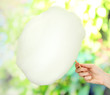 Hand holding stick with cotton candy, on bright background