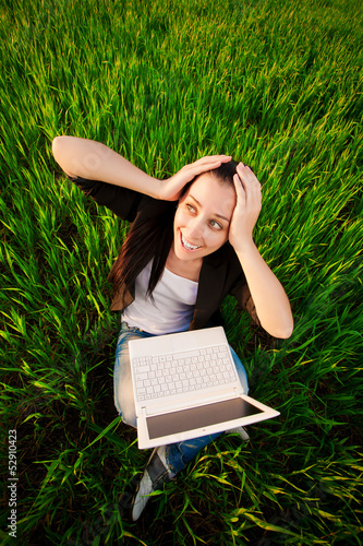 Photo: woman in a green field with a laptop. summer woman in a green field with a laptop. summer