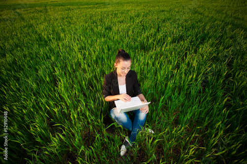 Photo: puzzled woman in a green field with a laptop. summer puzzled woman in a green field with a laptop. summer