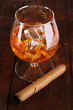 Brandy glass with ice on wooden background