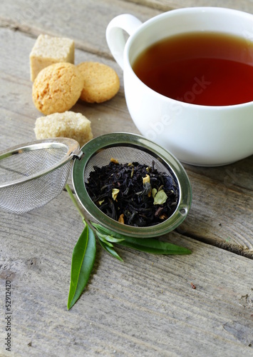 Photo: black tea leaves in a metal strainer on a wooden table black tea leaves in a metal strainer on a wooden table