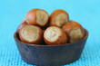 Hazelnuts in miniature wooden bowl, close up on blue background