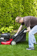 Mature man installing grass bag on old lawnmower