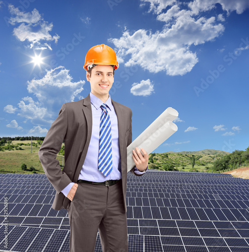 Photo: Architect wearing helmet and holding blueprints, with solar phot Architect wearing helmet and holding blueprints, with solar phot