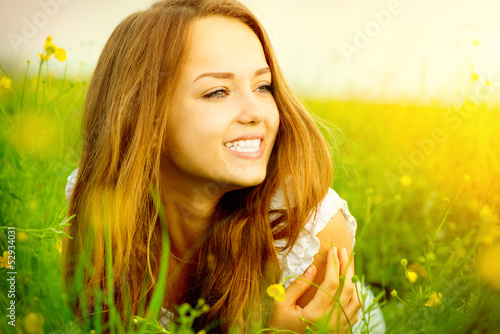 Photo: Beauty Girl in the Meadow lying on Green Grass with wild Flowers Beauty Girl in the Meadow lying on Green Grass with wild Flowers