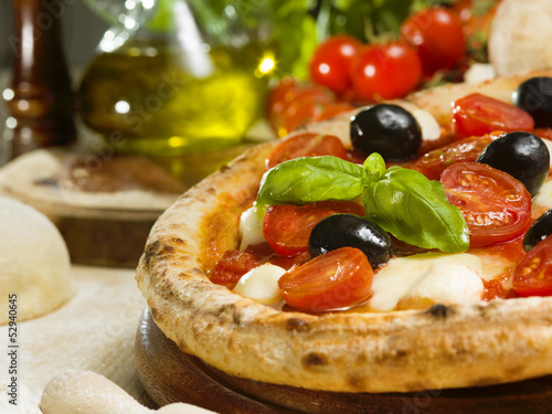 Photo: Italian pizza with tomato, mozzarella, basil and olives Italian pizza with tomato, mozzarella, basil and olives