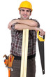 Carpenter with wood slats and saw