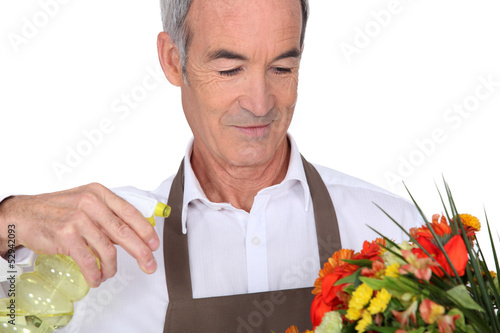 Photo: Senior man spraying water on flowers Senior man spraying water on flowers