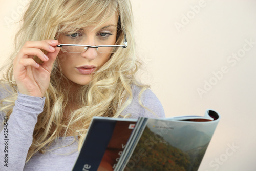 Photo: Woman with glasses reading magazine Woman with glasses reading magazine