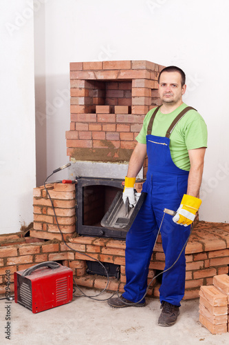 Photo: Worker mounting the door of a brick masonry heater Worker mounting the door of a brick masonry heater