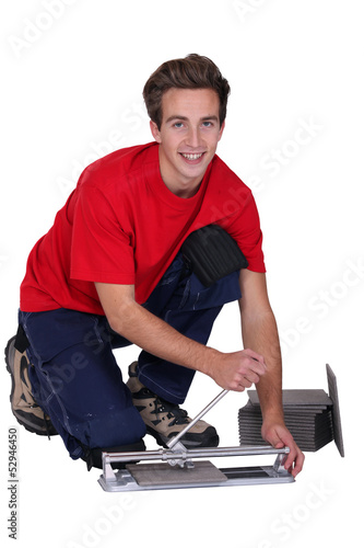 Photo: Young man using a tile cutter Young man using a tile cutter