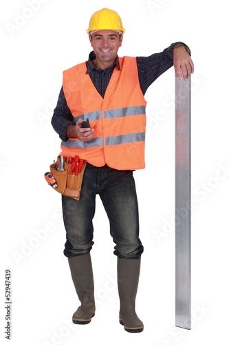 Photo: carpenter all smiles with arm resting on metallic post carpenter all smiles with arm resting on metallic post