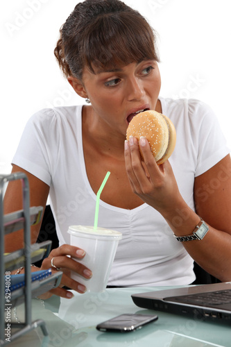 Photo: hungry female executive eating hamburger hungry female executive eating hamburger