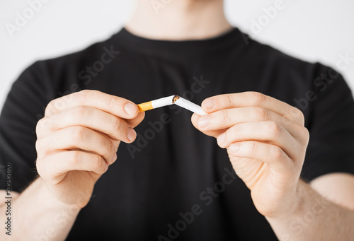 Photo: man breaking the cigarette with hands man breaking the cigarette with hands