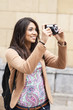 Young smiling woman taking pictures by city.