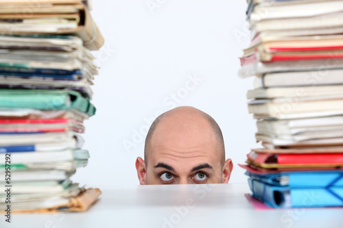 Photo: Man peeking through stacks of folders Man peeking through stacks of folders