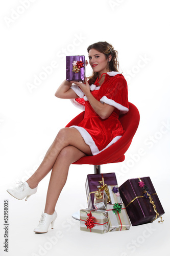 Photo: Woman dressed as Mrs. Claus holding a present Woman dressed as Mrs. Claus holding a present