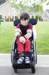Disabled little boy in wheelchair outdoors