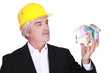 Grey-haired architect holding house made from bank notes