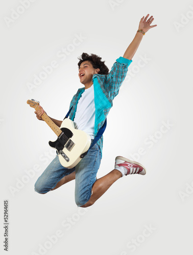 Photo: young man playing on electro guitar and jumping young man playing on electro guitar and jumping