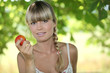 Blond woman in garden holding apple