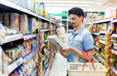 Photo: man in a supermarket buying a box of cornflakes man in a supermarket buying a box of cornflakes