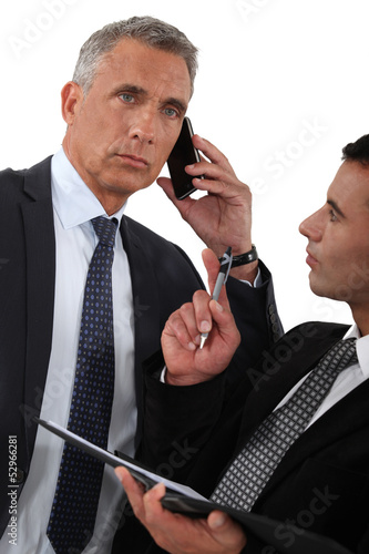 Photo: Man on the phone and writing assistant Man on the phone and writing assistant
