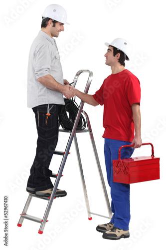 Photo: Two workers greeting each other with a hand-shake Two workers greeting each other with a hand-shake