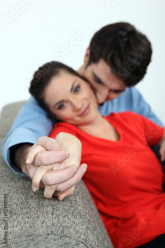 Photo: Couple holding hands on a sofa Couple holding hands on a sofa