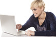 cute smiling blonde working on a laptop on white background