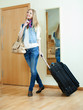 Happy girl with luggage near door