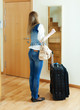 Long-haired girl with luggage looking in mirror