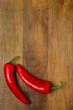 two red hot chili peppers on a wooden background